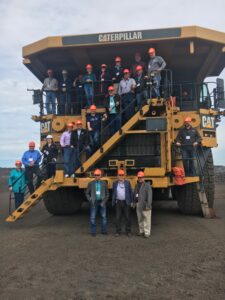 Legislators standing in front of and on top of a mine dump truck