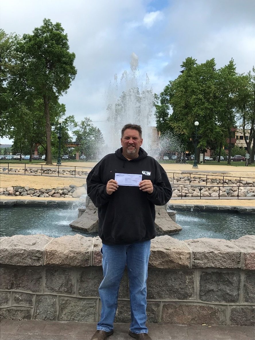 John Arbogast presenting a check in front of the Olcott Park Fountain