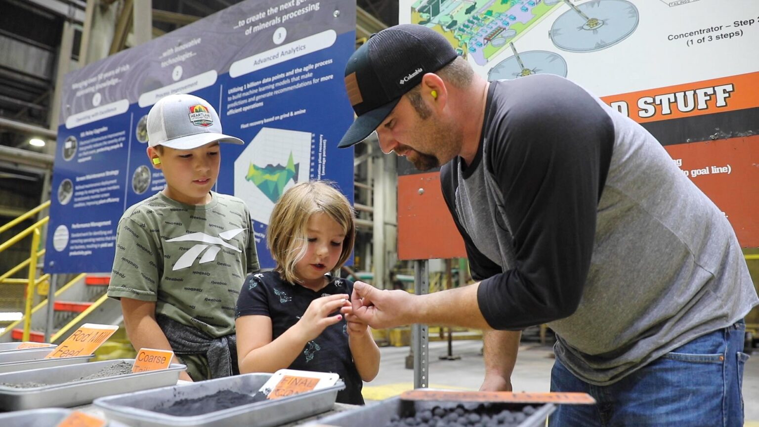 A father shows his children materials he works with at the mine