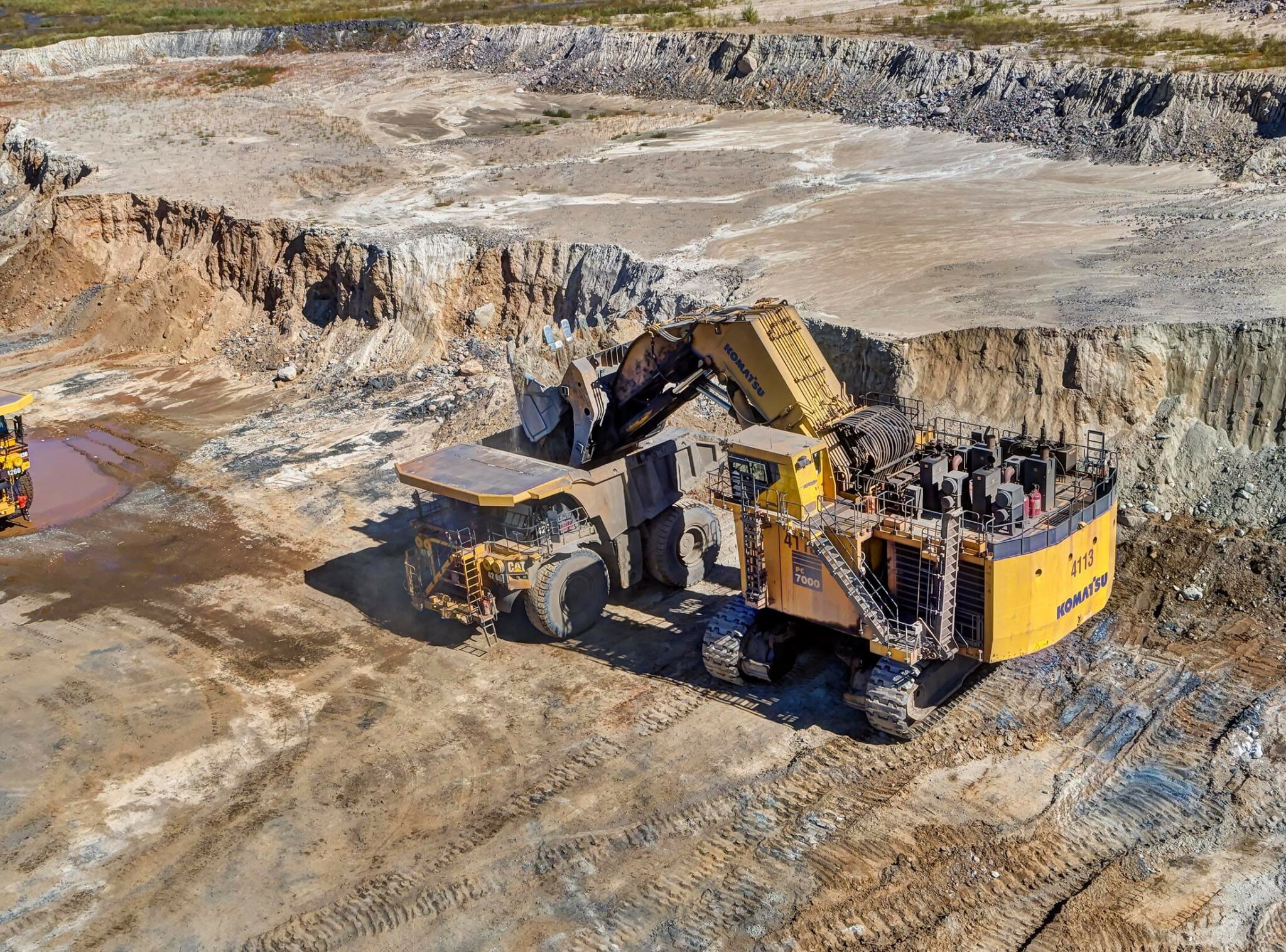 A mine shovel empties dirt into a nearby dumptruck