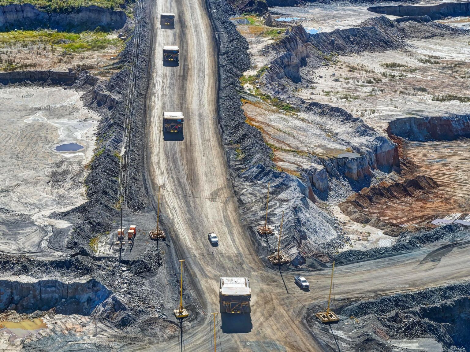 Mine vehicles travelling down a sandy road