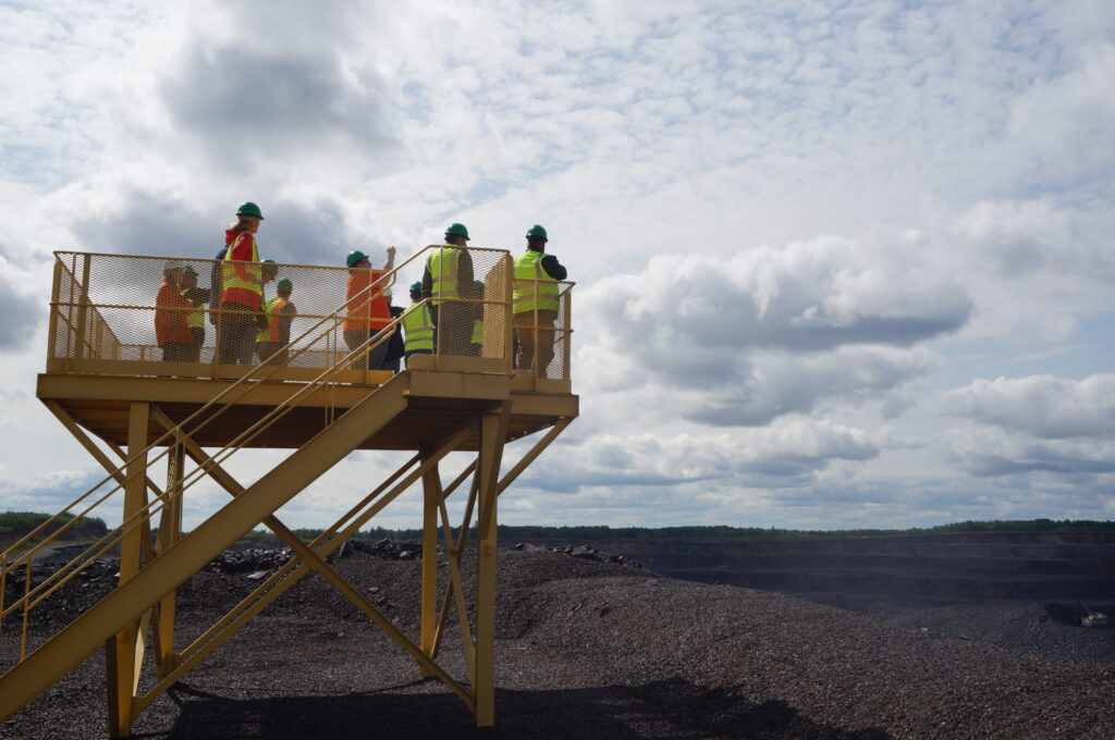 Iron Ore Alliance members standing atop a viewing platform over the mining range