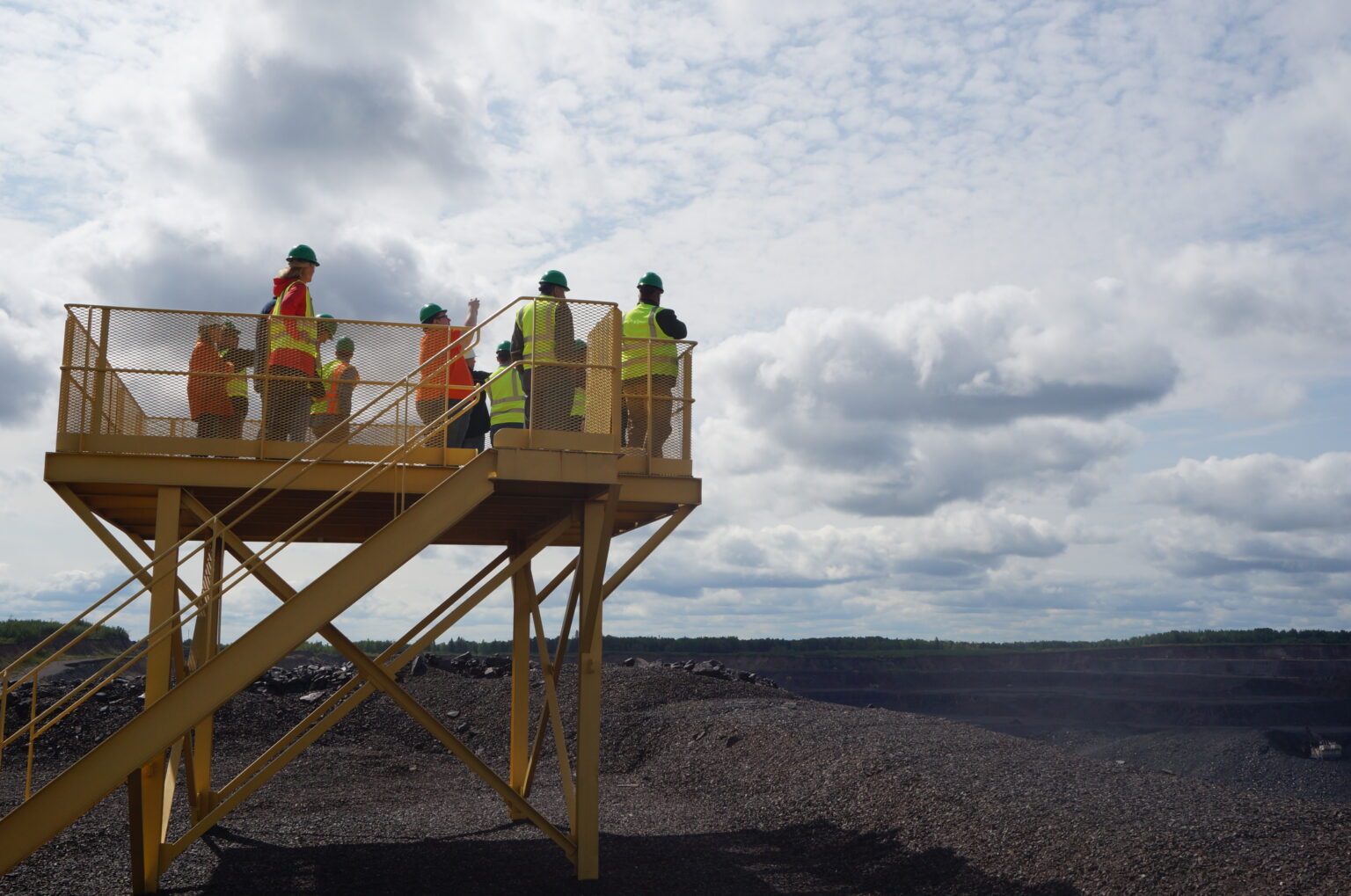 Iron Ore Alliance members standing atop a viewing platform over the mine