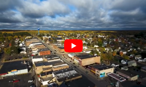 An aerial shot of a town in the Iron Range and the YouTube play icon